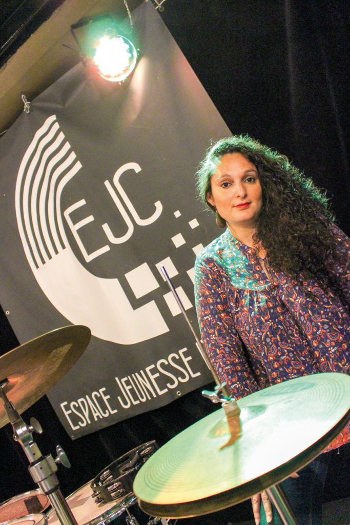 Mélissa Aït Mesghat, directrice de l’Espace Jeunesse et Culture de Soissons, pose pour la photo devant le logo de l’association.